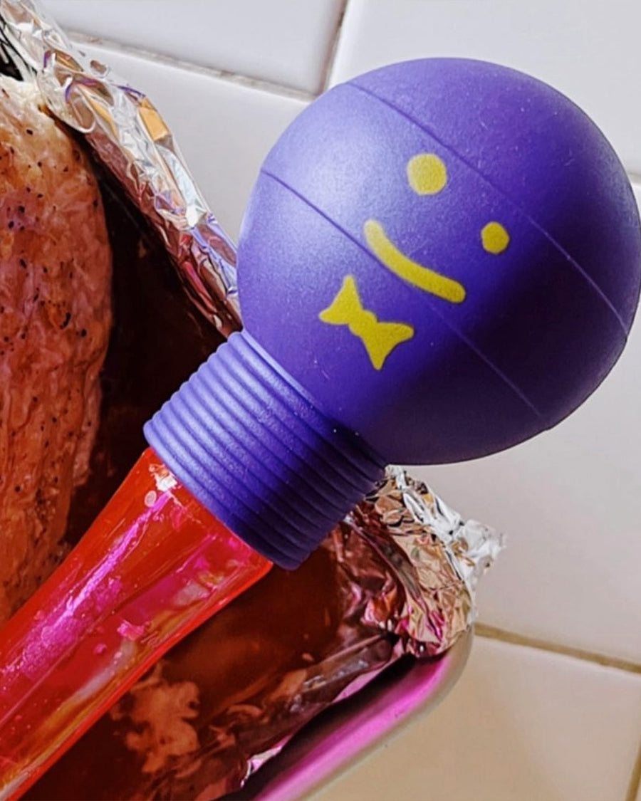 up close of pink acrylic baster with purple and yellow smiley squeeze top