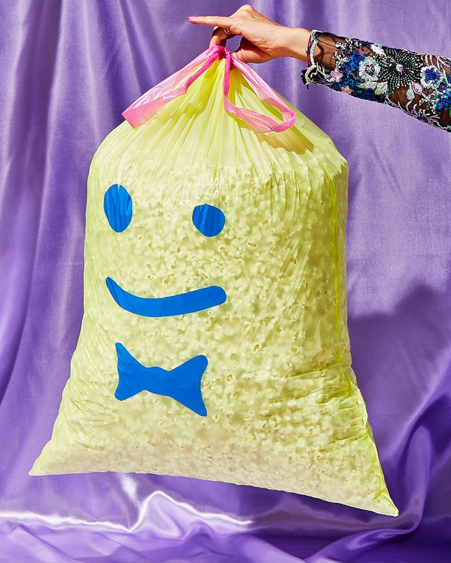 model holding yellow trash bags with blue smiley face print