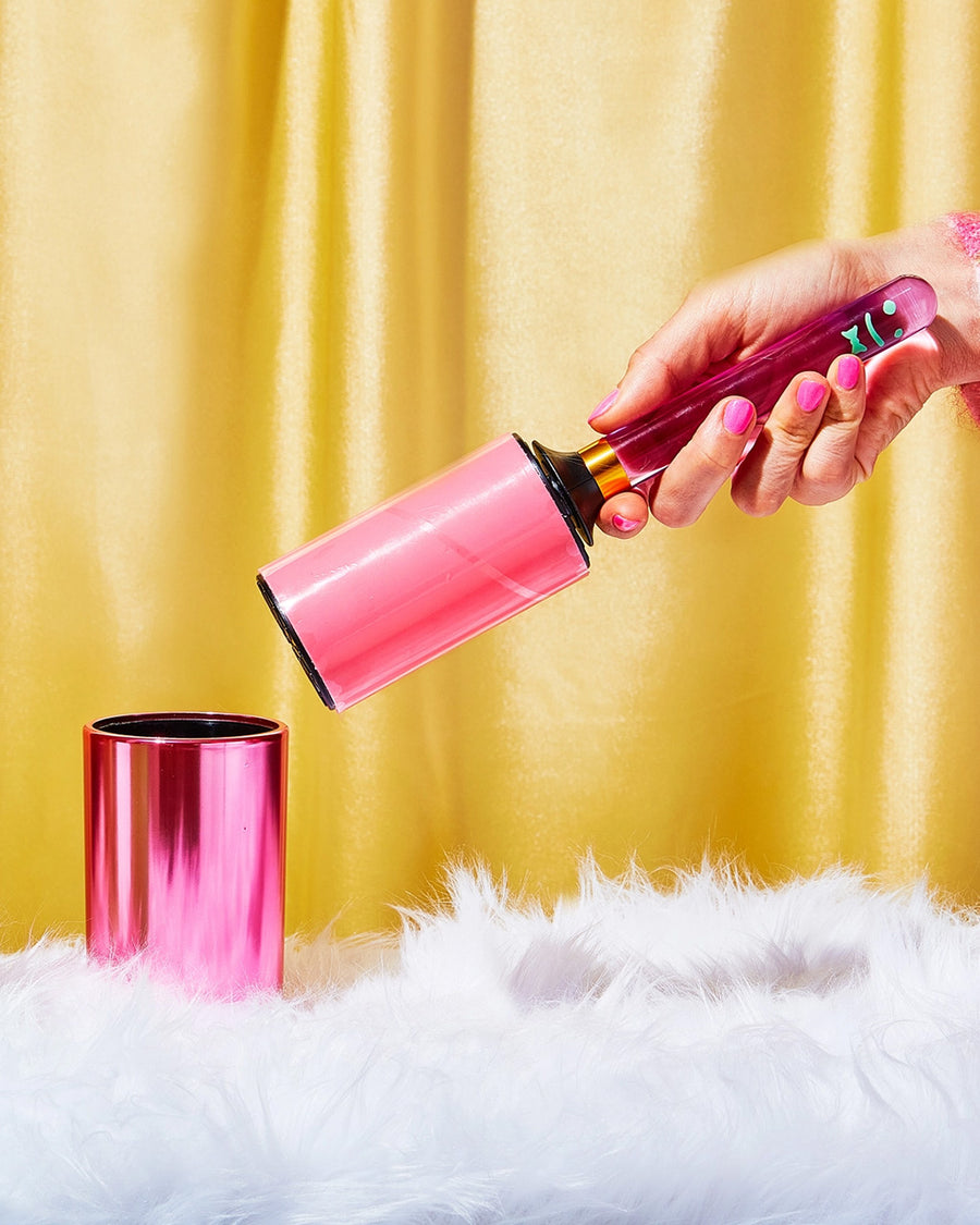 model holding hot pink metallic lint roller and green smiley top