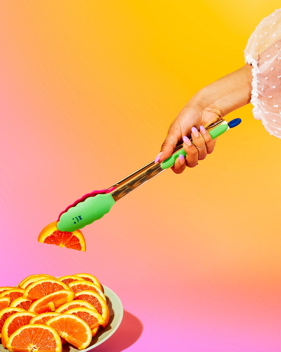 model using gold tongs with pink and green silicone bottoms