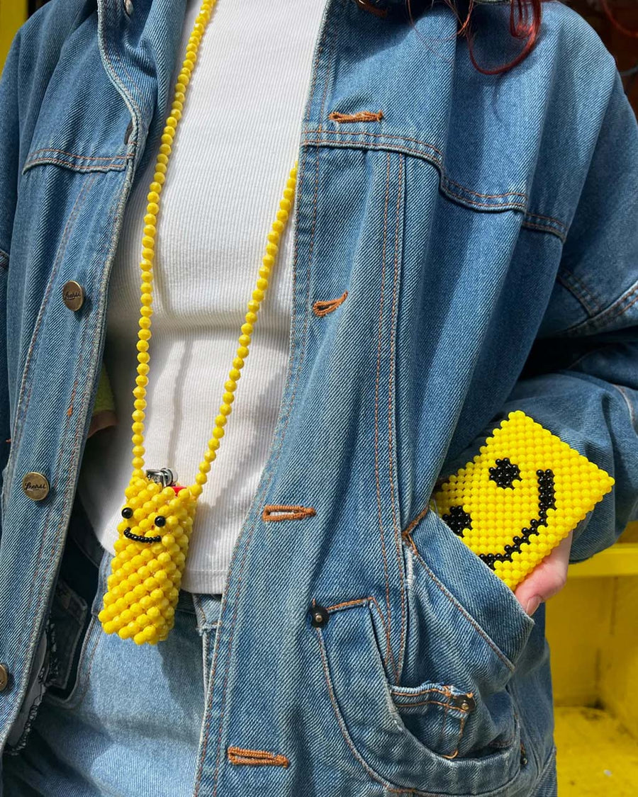 model pulling yellow smiley face beaded cardholder out their pocket