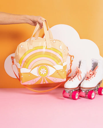 model holding trippy skate bag with pink, orange and yellow colors, abstract stars and eye design with white skates next to it