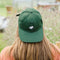 model wearing forest green hat with embroidered snoopy face