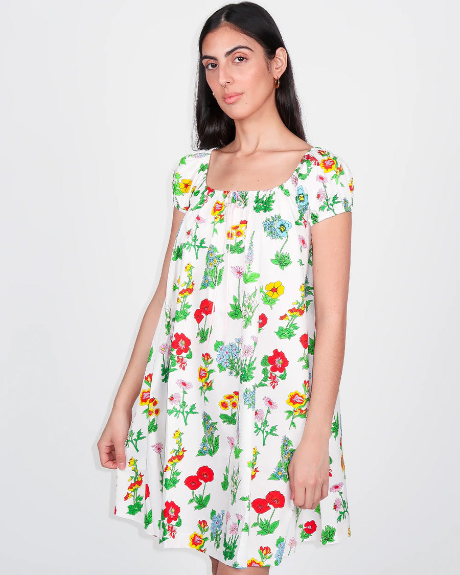 model wearing white mini dress with flowy skirt and colorful floral print