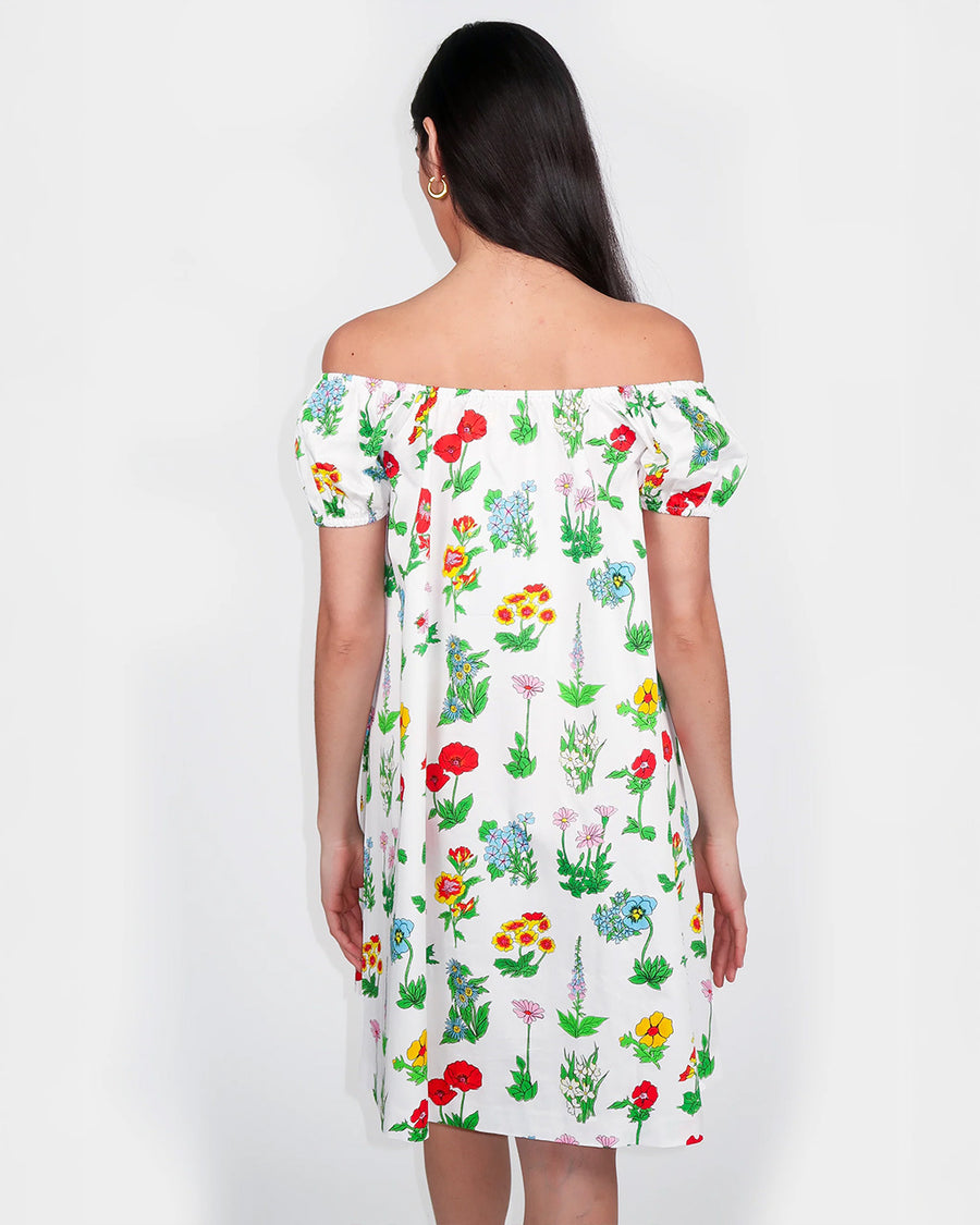 back view of model wearing white mini dress with flowy skirt and colorful floral print