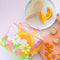 pink pouch with handle and double zippers with colorful 70's type floral print surrounded by snacks and food