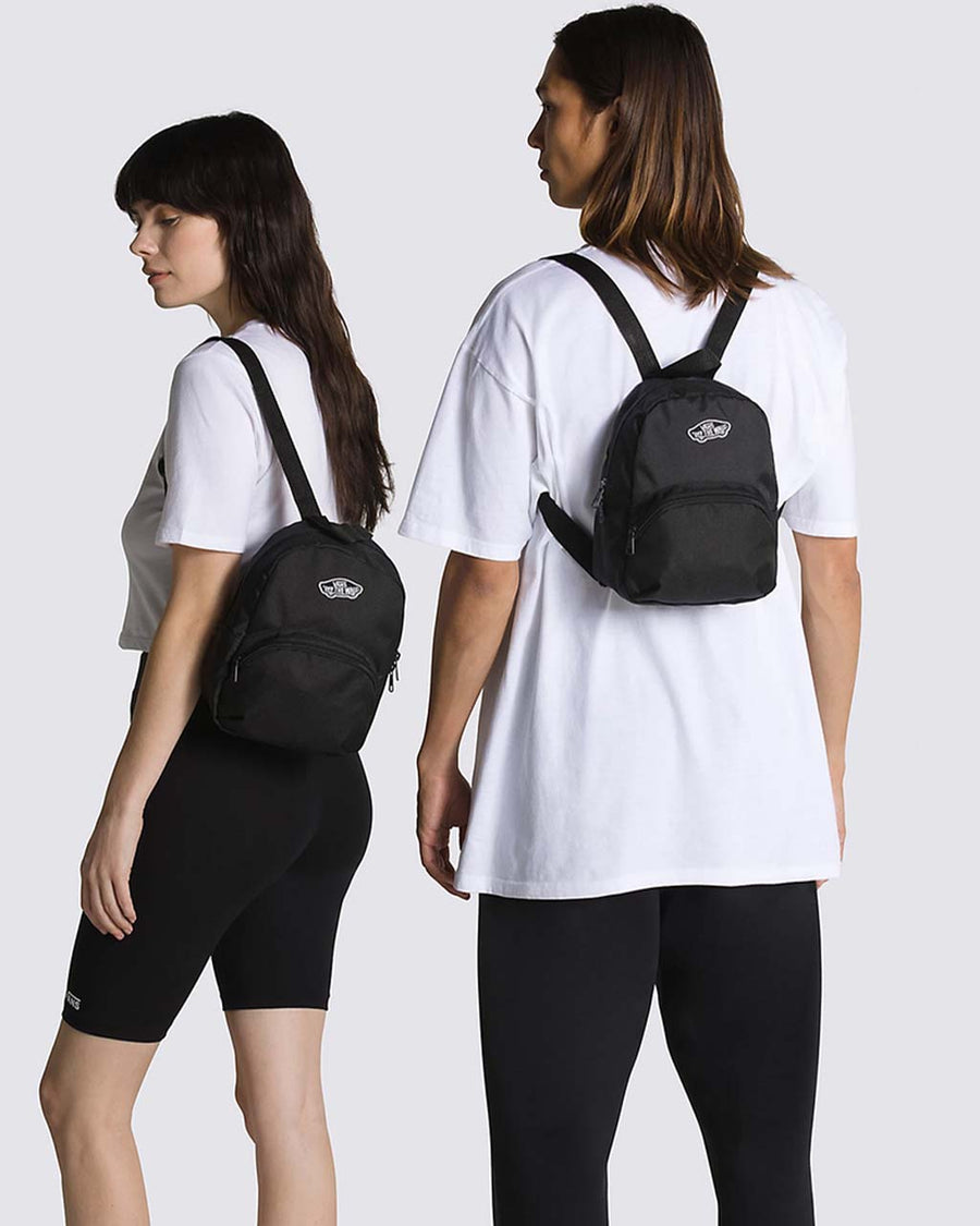 models wearing black mini backpack with skateboard 'vans off the wall' patch and front zip pocket