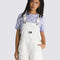 model wearing white cotton short overalls with patch front pocket, adjustable straps, side pockets and vans logo patch