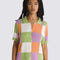 model wearing green, purple, orange, and white checkered button front sweater top