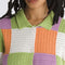 up close of model wearing green, purple, orange, and white checkered button front sweater top