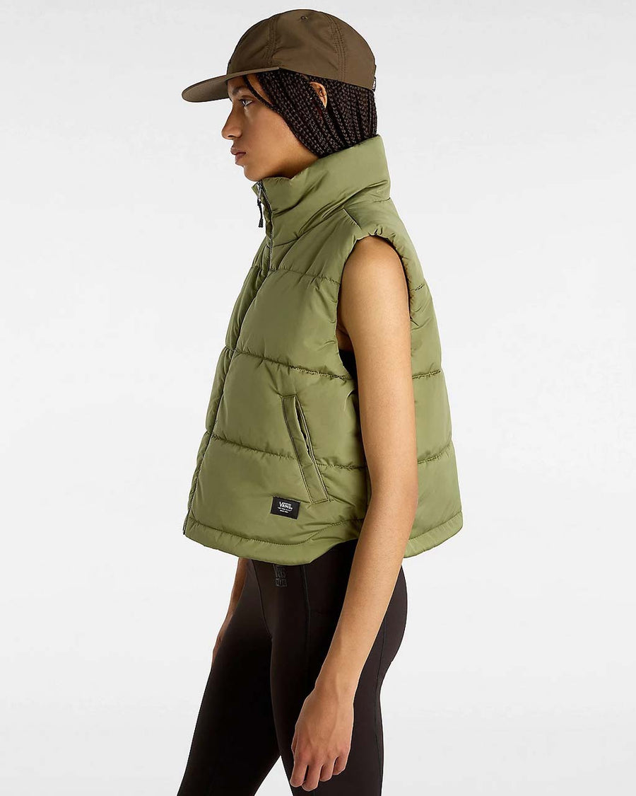 side view of model wearing green puffer vest with high neck and side pockets