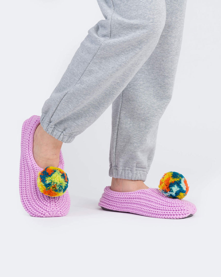 model wearing lilac knitted slip on slipper socks with rainbow pom