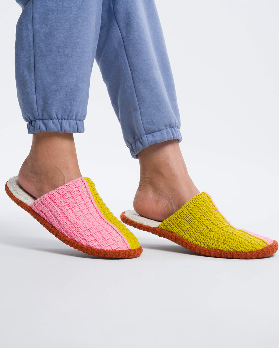 model wearing split pink and olive green knit slippers with a fuzzy inside