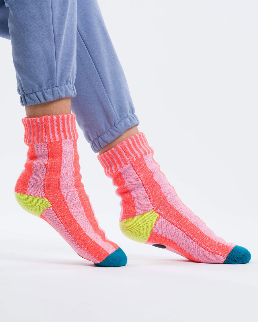 model wearing pink striped socks with yellow and blue trim and non-slip bottom