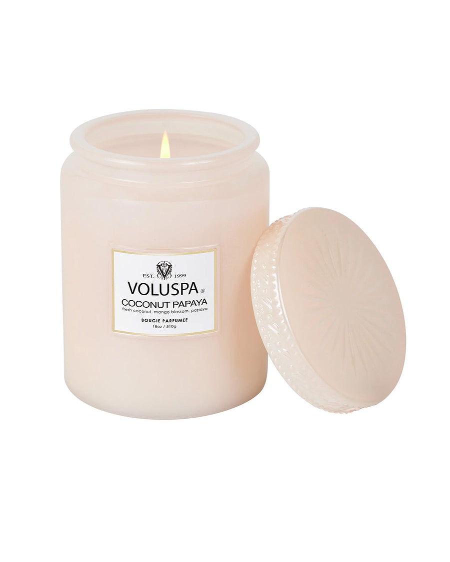 lit large 18oz. coconut papaya scented candle in a light pink embossed vessel