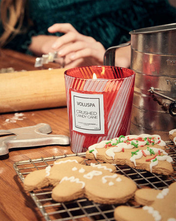 red and white striped candy cane scented candle next to holiday cookies