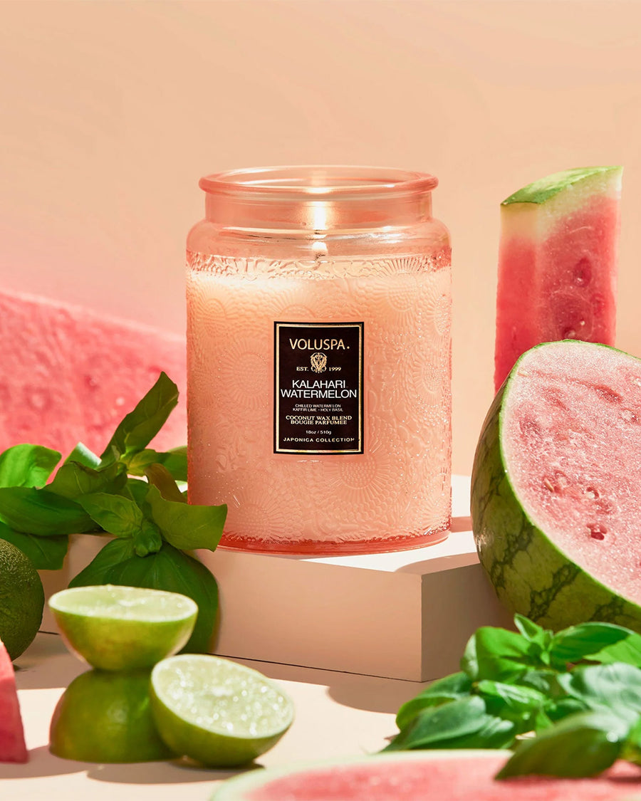 large 18oz. watermelon scented candle in a coral embossed vessel surrounded by watermelons and lime