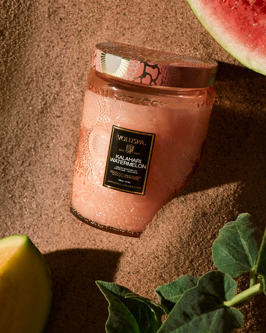 large 18oz. watermelon scented candle in a coral embossed vessel in the sand