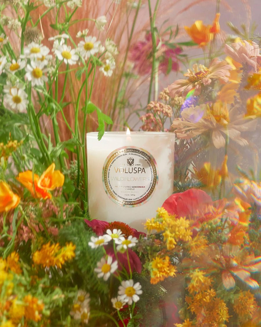 white wildflower scented candle and box surrounded by flowers