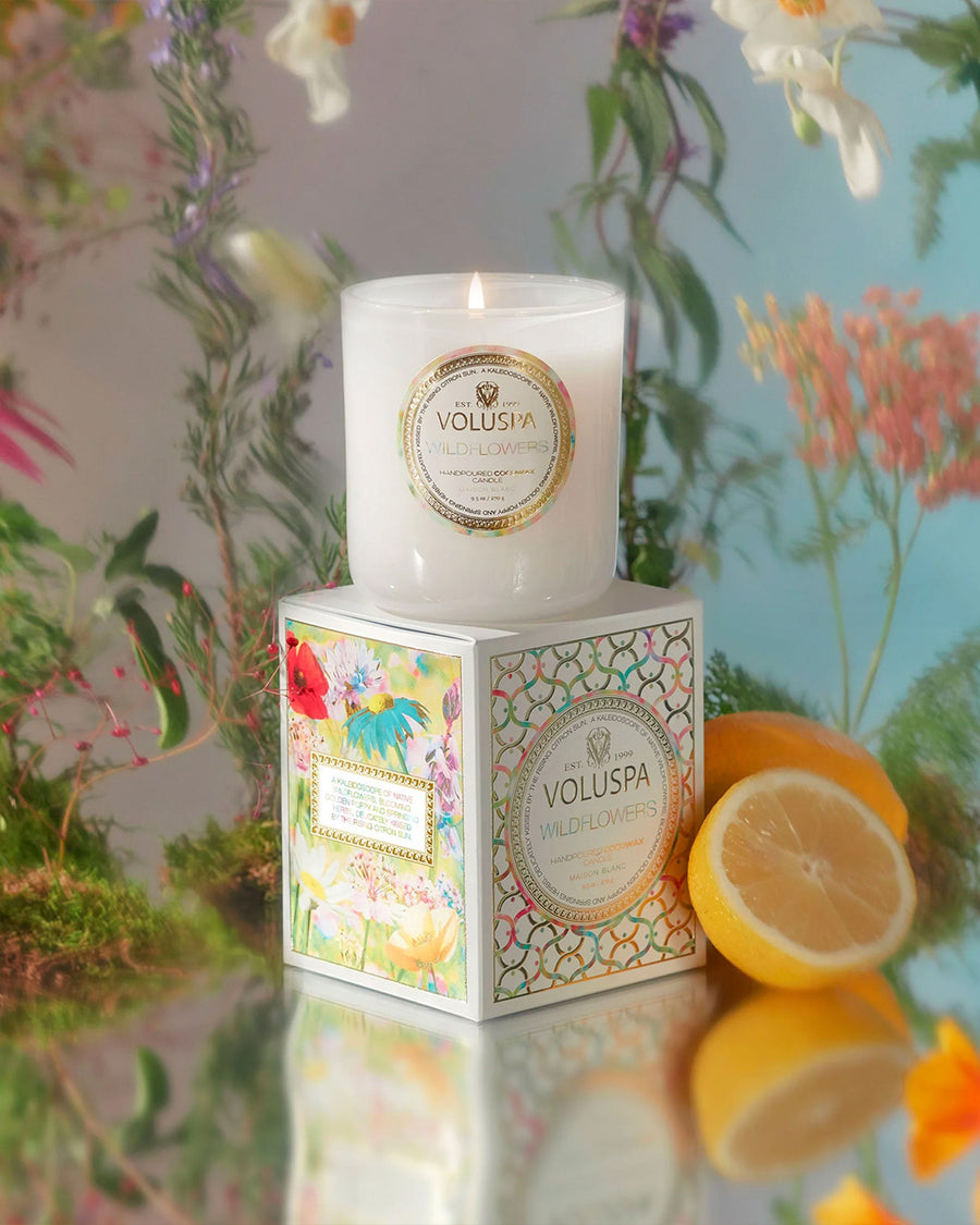 white wildflower scented candle and box surrounded by lemons and flower background