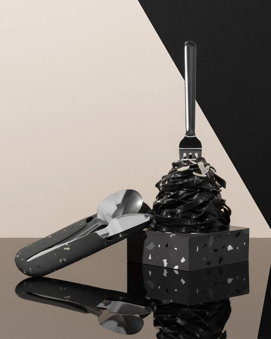 charcoal terrazzo utensil holder with spoon, fork and knife next to a cake