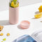 glass wide mouth water bottle with blush silicone grip sleeve and matching lid filled with fruit and veggies