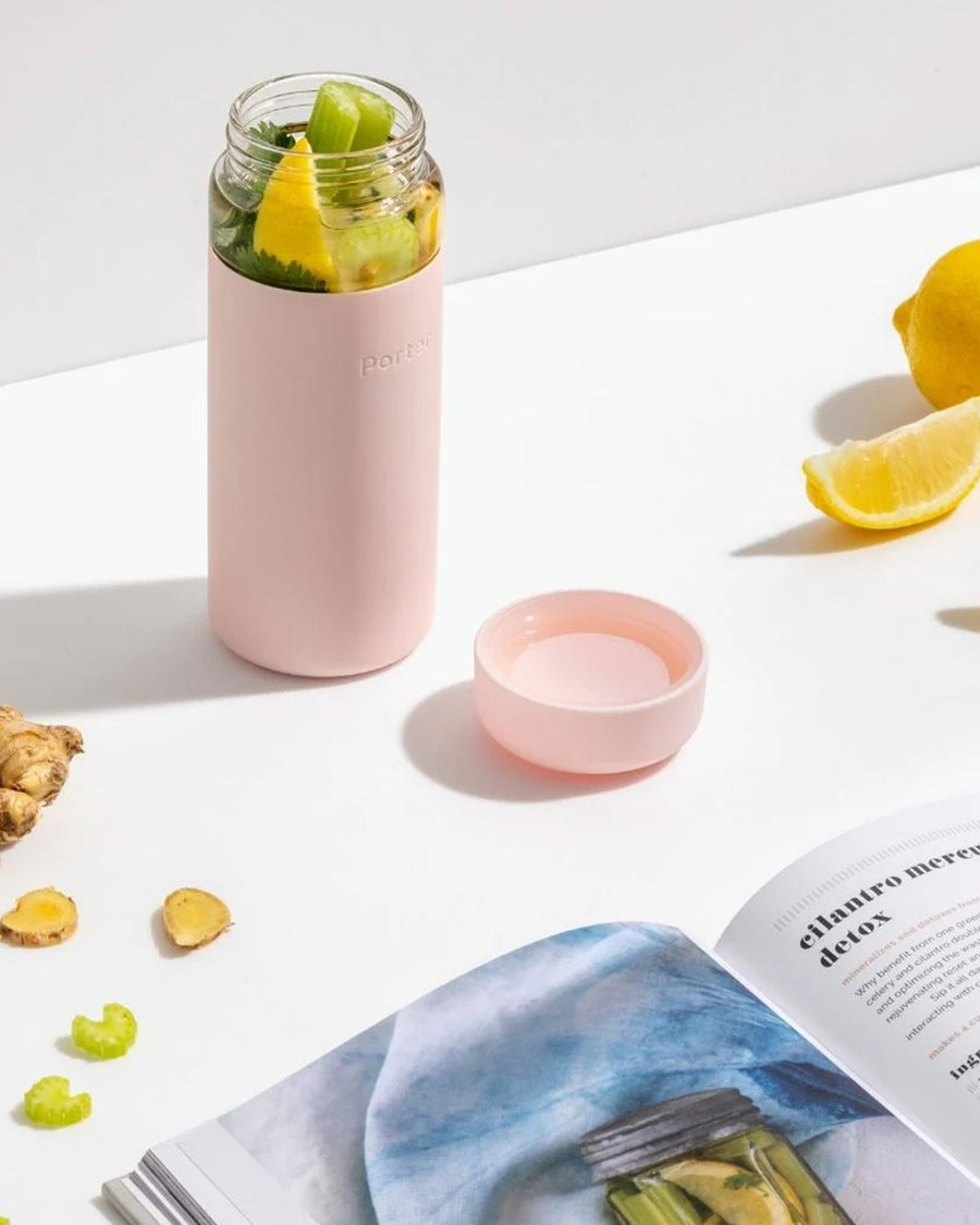 glass wide mouth water bottle with blush silicone grip sleeve and matching lid filled with fruit and veggies
