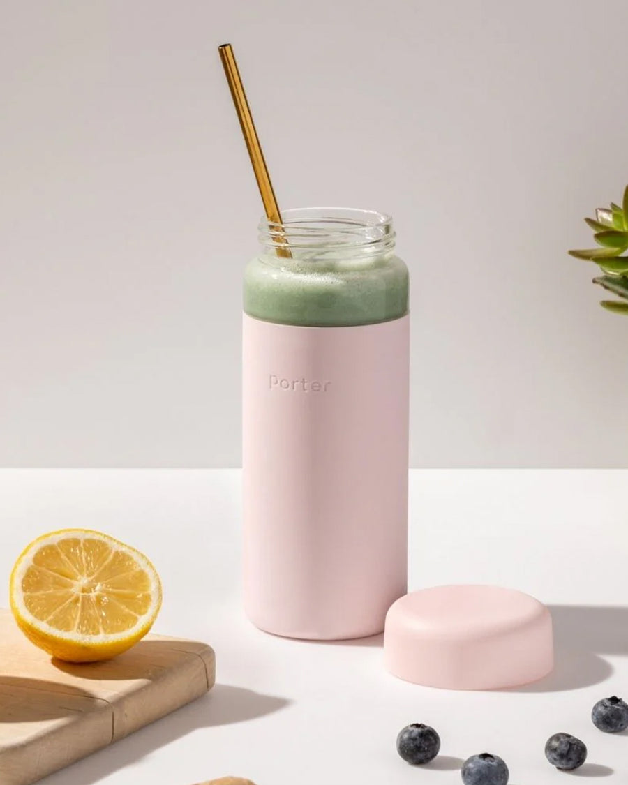 glass wide mouth water bottle with blush silicone grip sleeve and matching lid with green shake inside