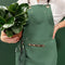 model wearing green apron with leather straps and front pockets