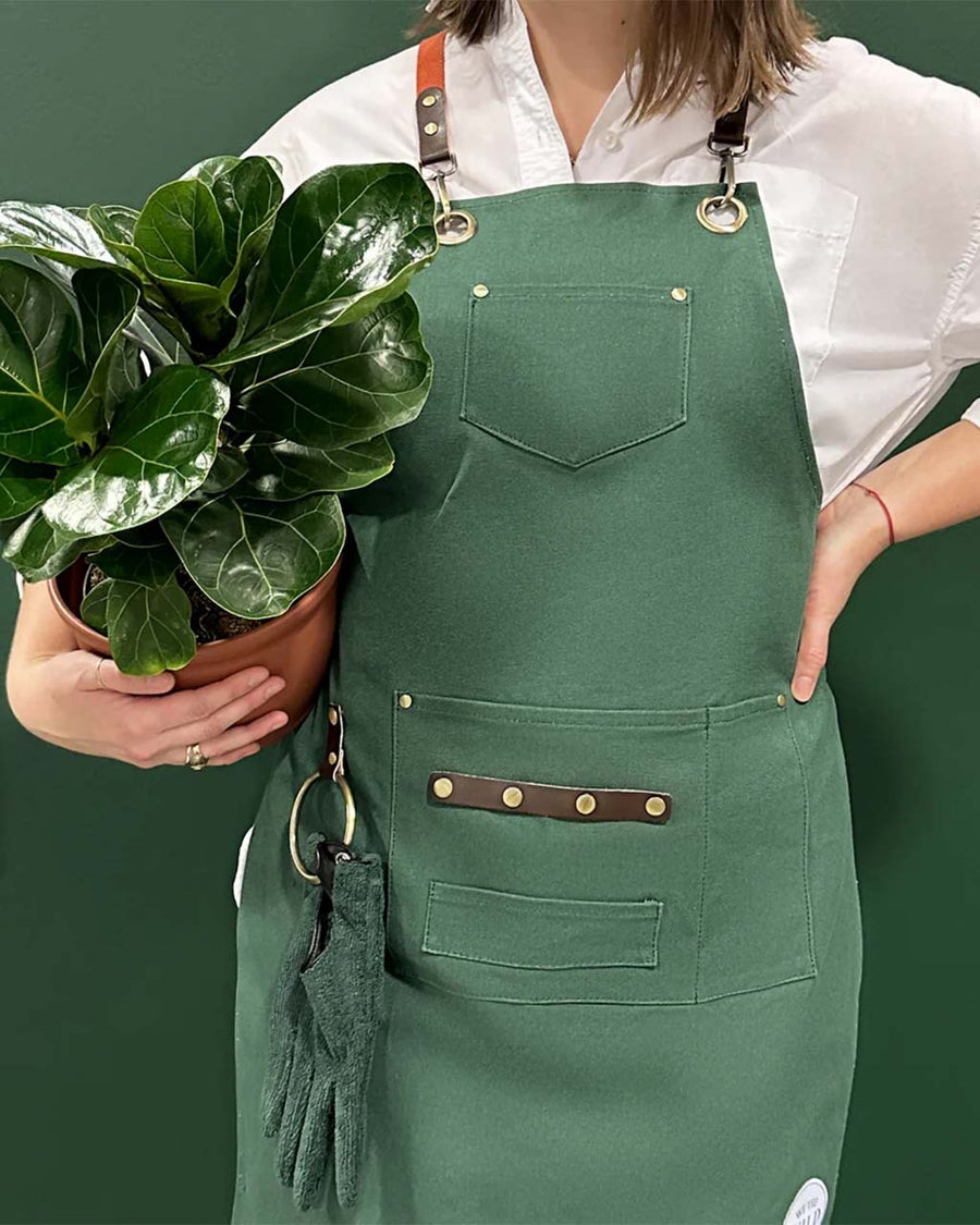 model wearing green apron with leather straps and front pockets