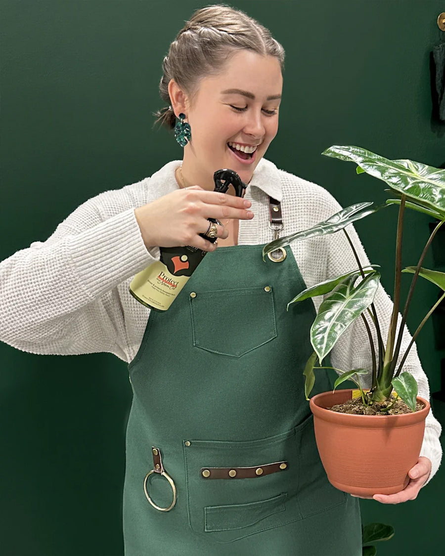 model wearing green apron with leather straps and front pockets