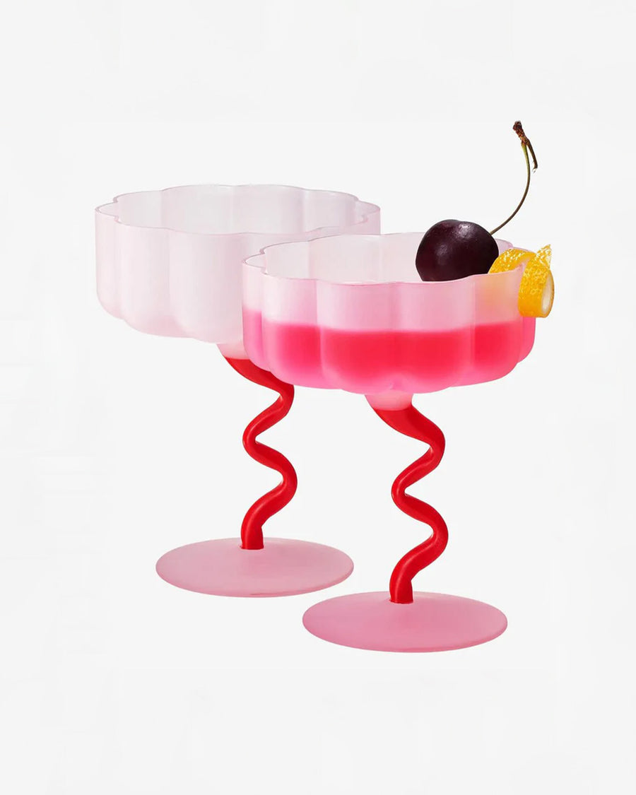 set of two pink and red frosted coupe glasses with a beverage inside