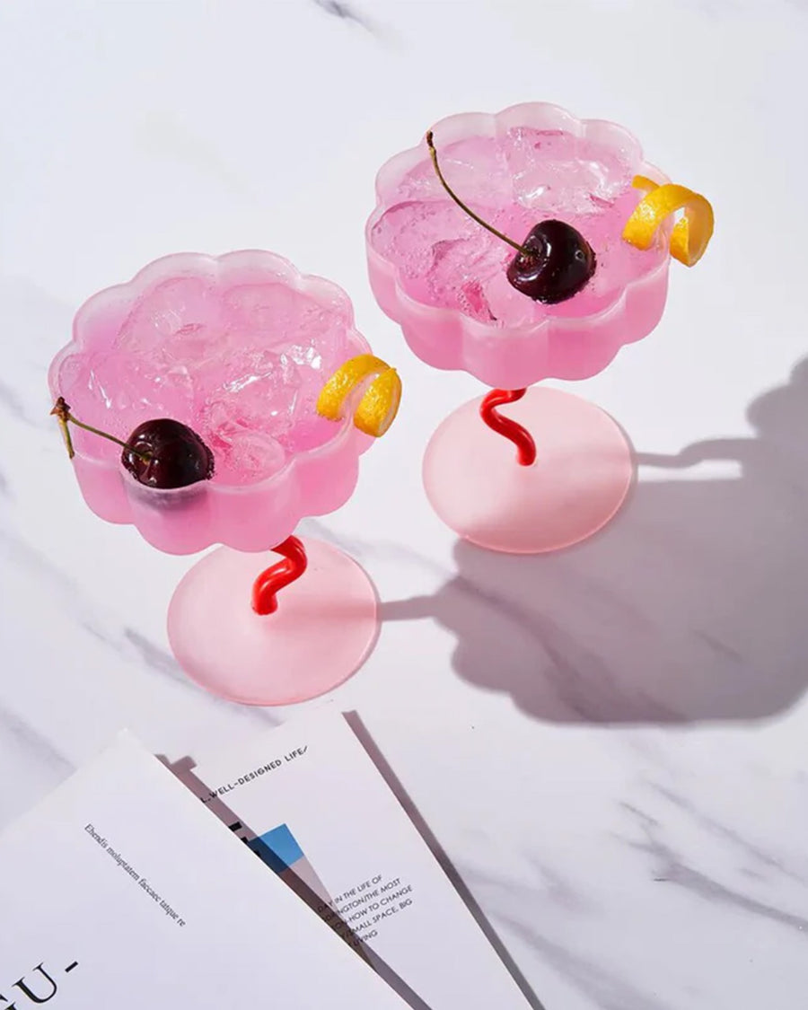 top view of set of two pink and red frosted coupe glasses with a beverage inside