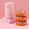 pink terrazzo 16 oz. reusable coffee mug with lid next to a stack of donuts