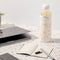 20 oz. glass water bottle with white terrazzo silicone cover on a desk