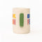 side view of cream ceramic coffee mug with green handle and  colorful 'book person' across the front and smiley face inside