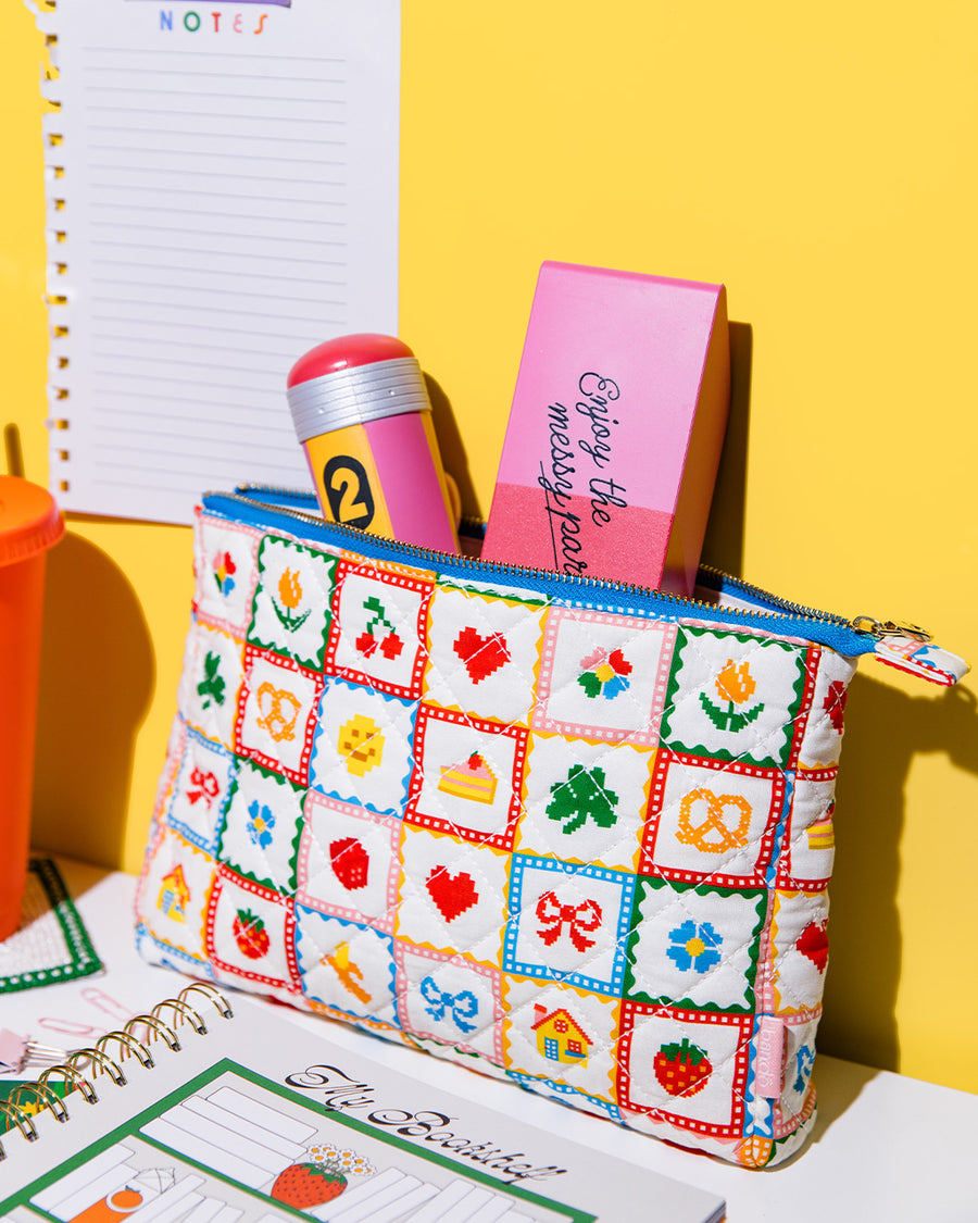  white quilted pouch with various hearts, fruits, smiley faces with eraser and pencil de-stress balls sticking out of the top