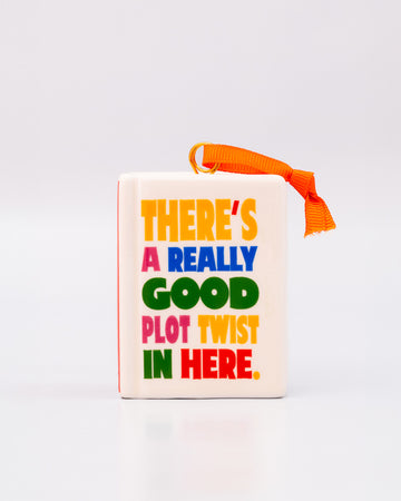 ceramic book shaped ornament with 'there's a really good plot twist in here' on the front and back