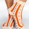 model wearing cream chenille socks with ruffle top with orange stripes and multicolor dots