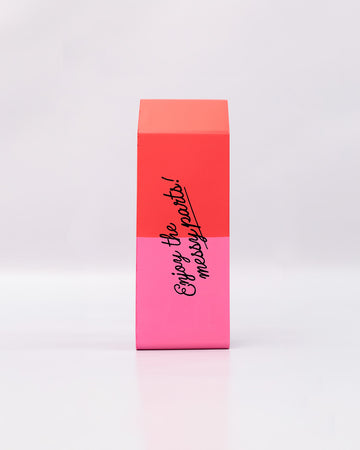 pink and red eraser shaped de-stress ball with black 'enjoy the messy parts' across the front