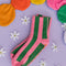 pink and green vertical stripe cozy socks with green grippies in the bottom