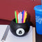 black magic 8 ball shaped vase with pens inside on a desk