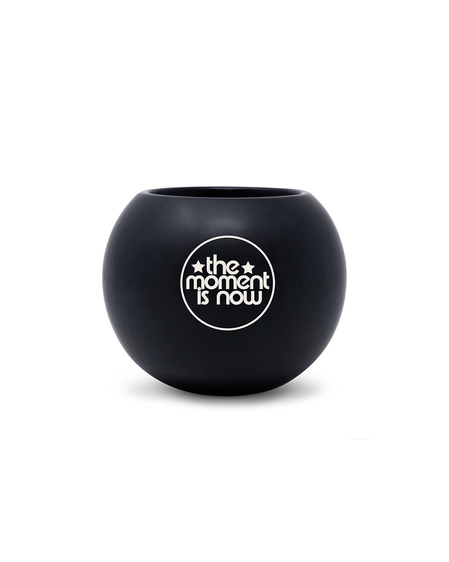 'the moment is now' back of black magic 8 ball shaped vase with pens inside