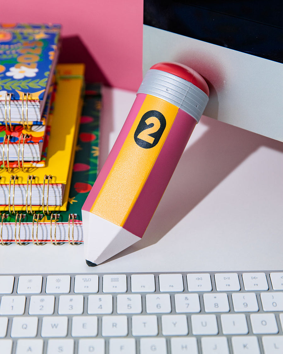 yellow and pink pencil shaped de-stress ball on a desk