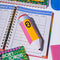 yellow and pink pencil shaped de-stress ball on a desk laying on a desk