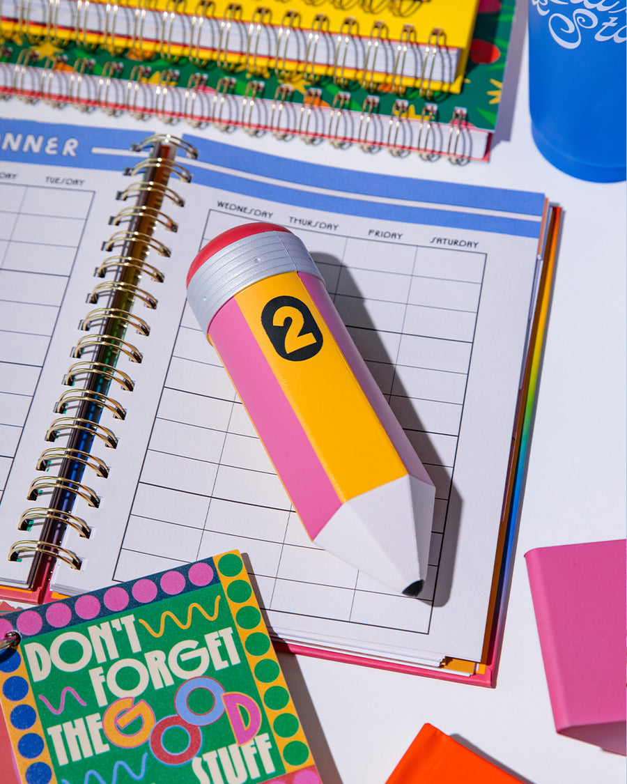 yellow and pink pencil shaped de-stress ball on a desk laying on a desk