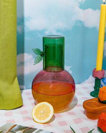 pink cherry shaped carafe with green lid/cup with leaf detail on a table