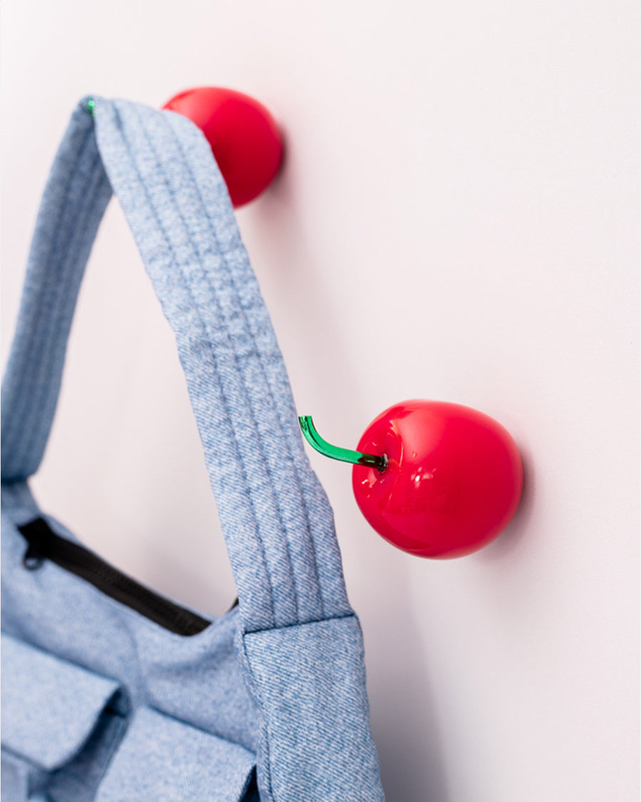 set of 2 cherry shaped hooks on a wall with a bag hanging from one