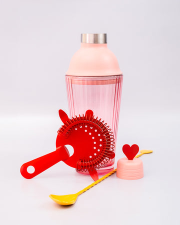 pink bar shaker with red heart top, red strainer, and yellow stirring stick