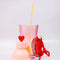 pink bar shaker with red heart top, red strainer, and yellow stirring stick